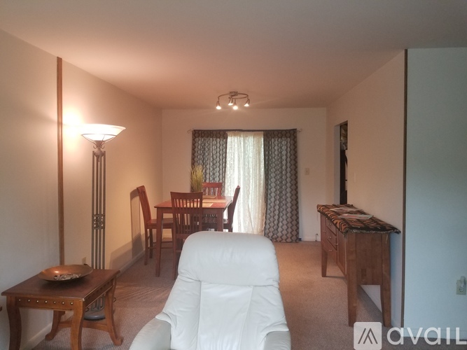 A living room with a white chair and a wooden table.