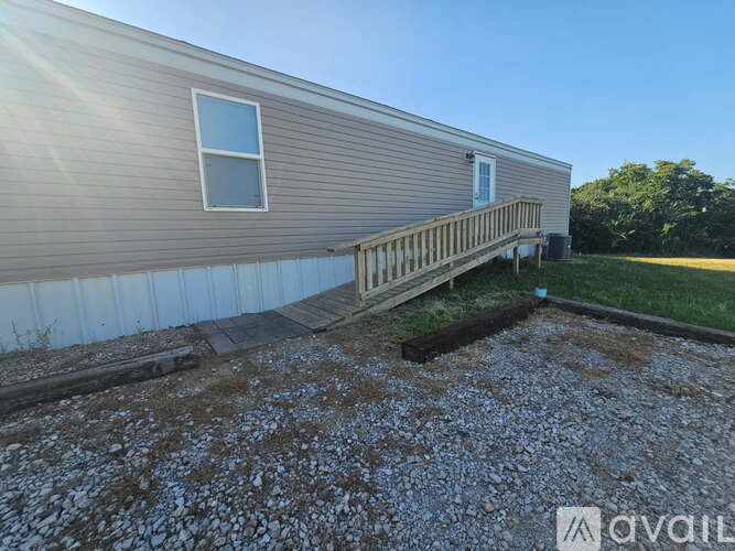A mobile home with a gravel driveway in front.