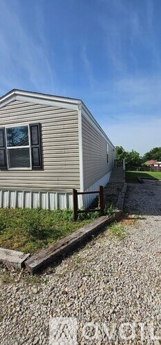 A mobile home with a gravel driveway in front.