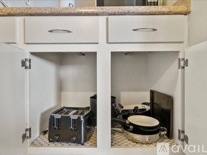 A kitchen cabinet with a toaster and a pan on the counter.
