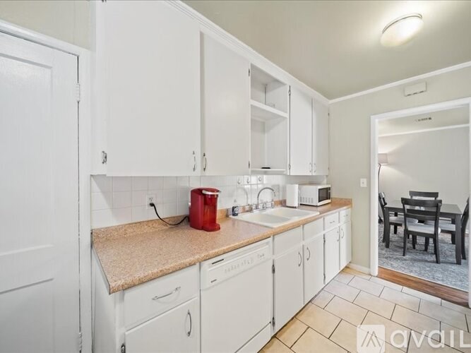A kitchen with white cabinets and a countertop with a red container on it.