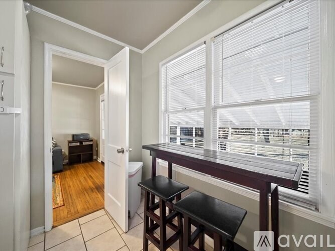 A room with a bar stool and a window with blinds.