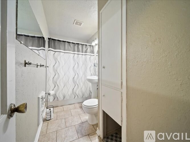 A bathroom with a toilet, a shower curtain, and a towel rack.