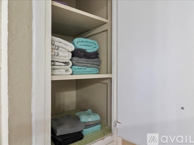 A white closet with towels on shelves.