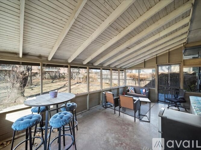 A sunroom with a table and chairs and a view of the outdoors.