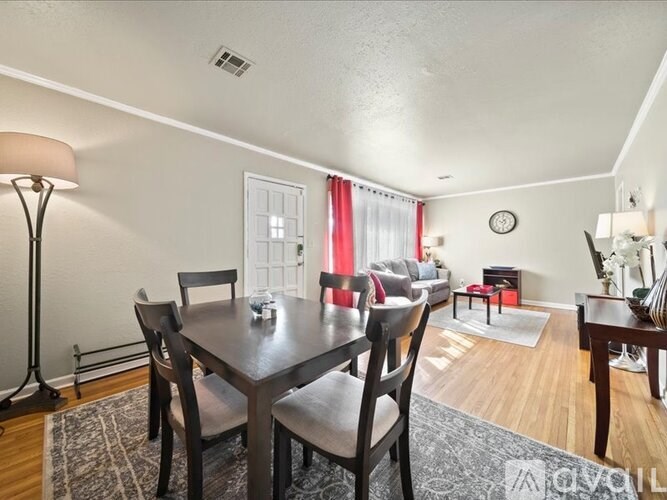 A dining room with a table set for two and a couch in the background.