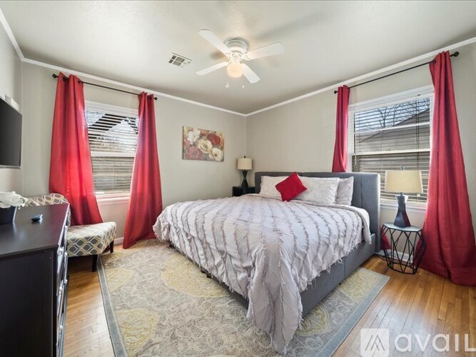 A bedroom with a large bed and red curtains.