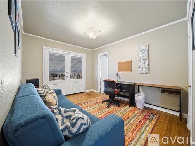 A living room with a blue couch and a rug.