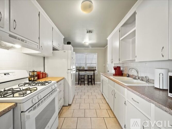 A kitchen with white cabinets and a tiled floor.