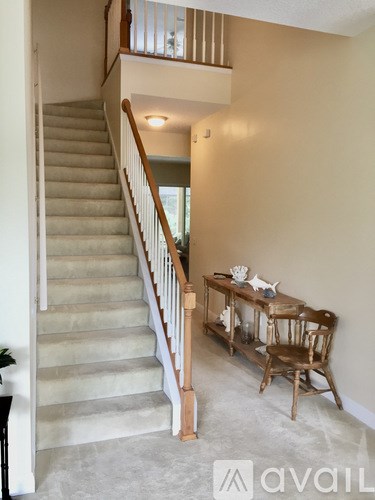 A staircase with a wooden handrail and a table with chairs in a room.