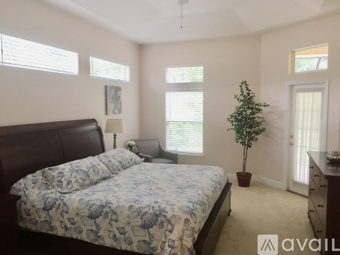 A bedroom with a bed, nightstand, and a plant.