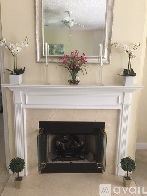 A white fireplace with a mirror above it and two flower vases on the mantle.
