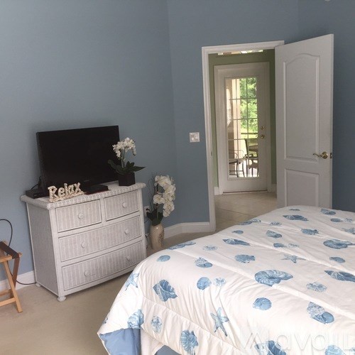 A bedroom with a bed, a dresser, and a television.