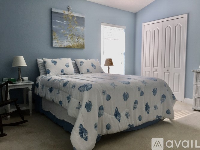 A bedroom with a bed covered in a blue and white comforter.
