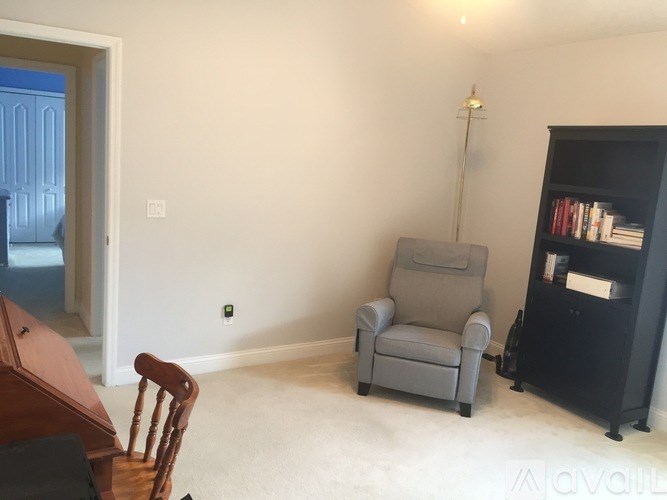 A living room with a grey chair, a wooden table, and a bookshelf.