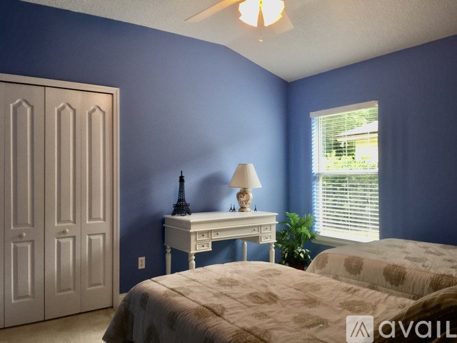 A bedroom with a white desk and a bed.