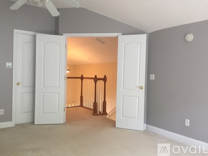A room with a ceiling fan and a doorway leading to a hallway.