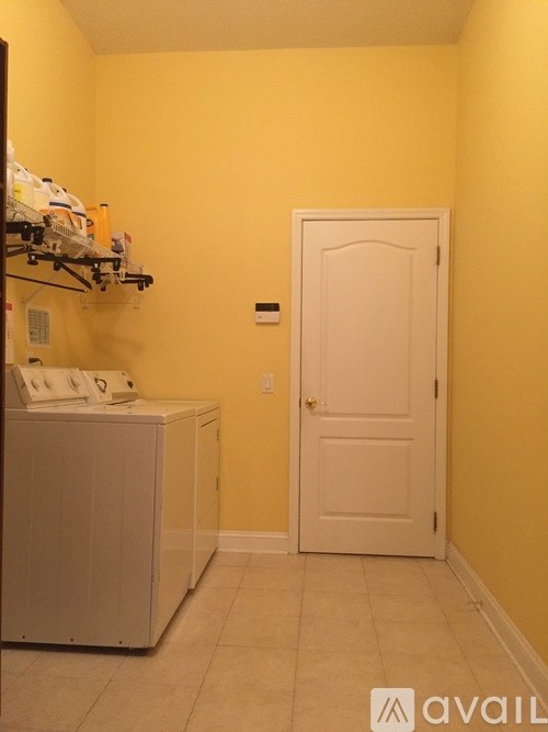 A small white fridge in a yellow room with a white door.