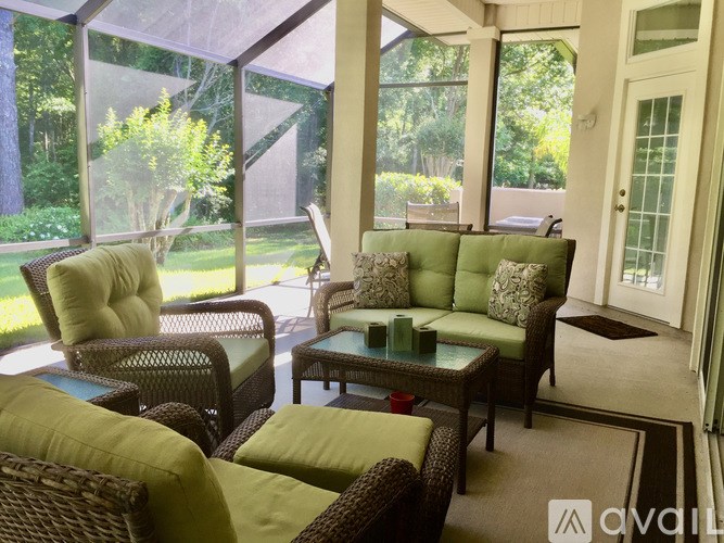 A patio with a table and chairs with green cushions.
