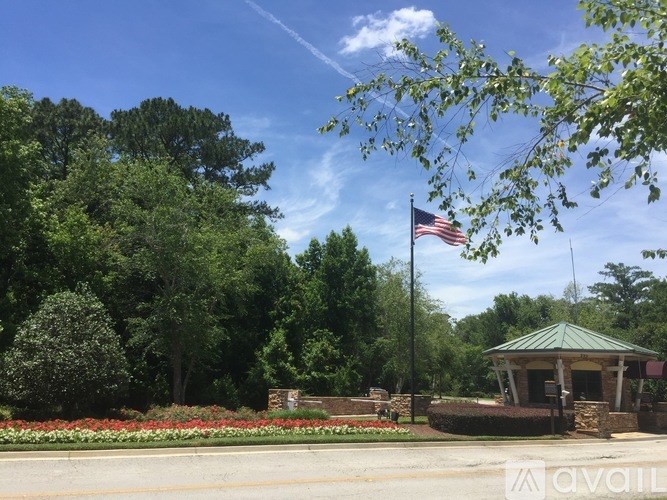 A gazebo with a flag on a pole stands in front of a green tree.