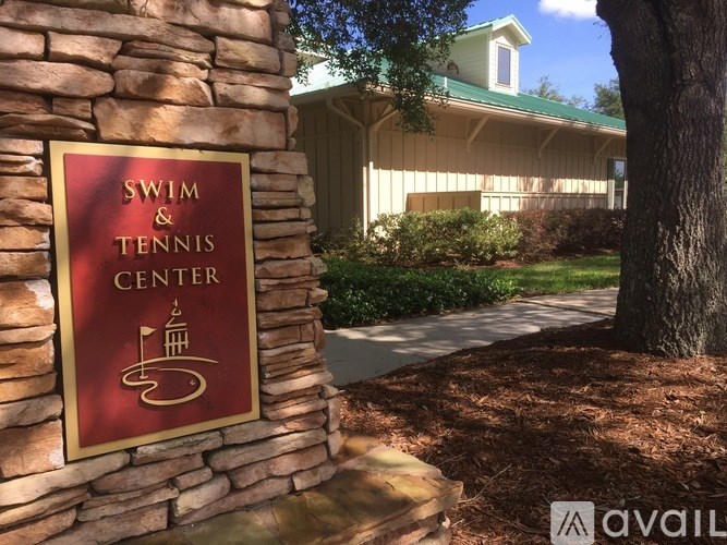 A sign for a Swim and Tennis Center is mounted on a stone pillar.