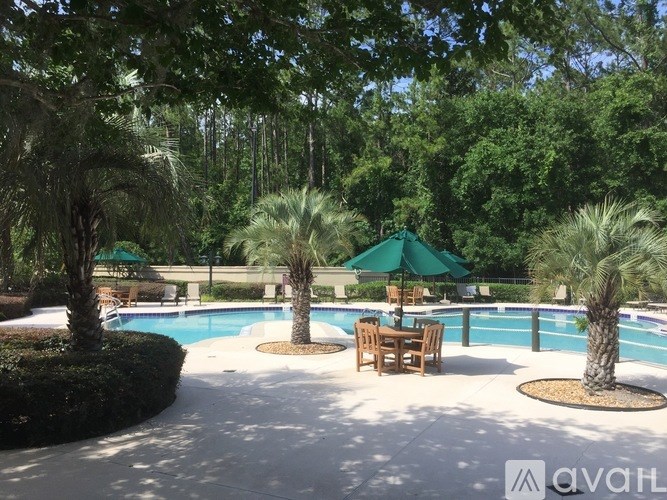 A pool surrounded by trees and a table with chairs.