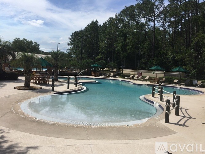 A large outdoor swimming pool surrounded by trees and lounge chairs.