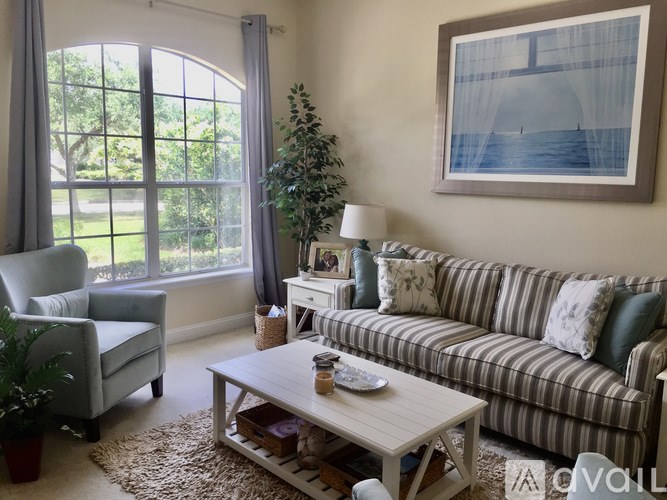 A living room with a couch, chair, and a painting on the wall.