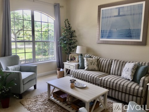 A living room with a couch, chair, and a painting on the wall.