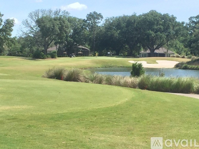 A golf course with a pond and a clubhouse in the background.