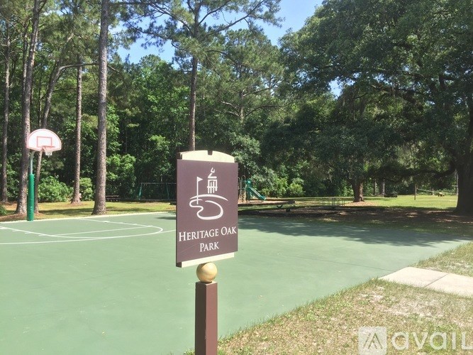 A sign for Heritage Oak Park stands in front of a basketball court.