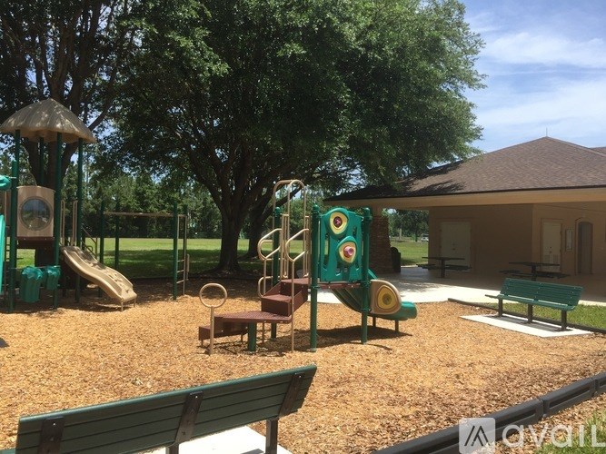 A playground with a green slide, a brown and green play structure, and a brown bench.