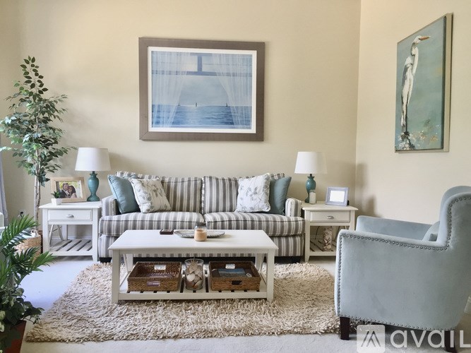 A living room with a striped couch, a grey armchair, and a coffee table with a tray on it.