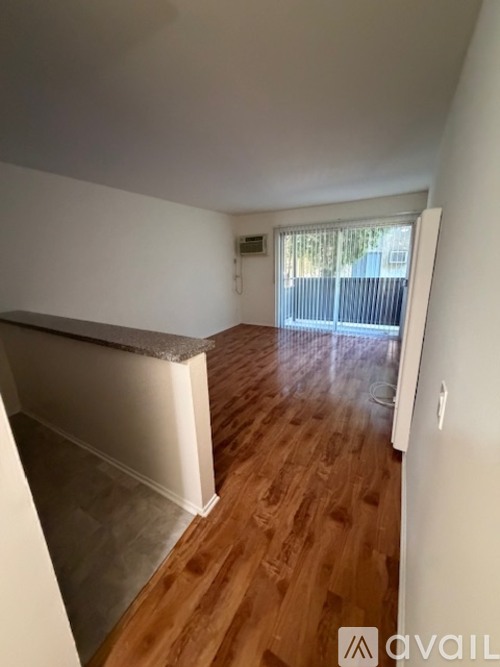 A room with wooden flooring and a window with blinds.
