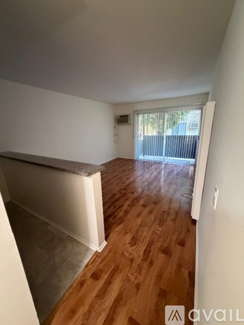 A room with wooden flooring and a window with blinds.