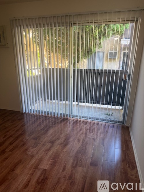 A room with a wooden floor and a sliding door with blinds.