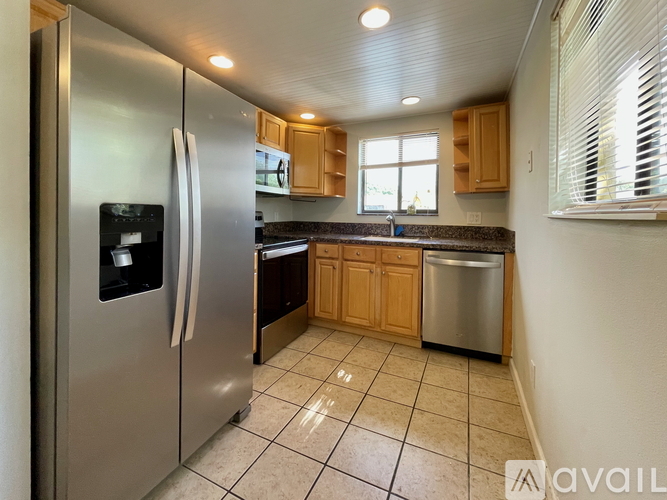 A kitchen with a stainless steel refrigerator and wooden cabinets.