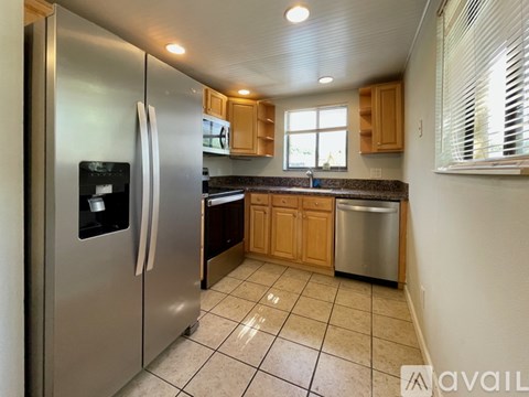 A kitchen with a stainless steel refrigerator and wooden cabinets.
