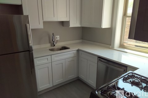 A kitchen with white cabinets and a stainless steel refrigerator.