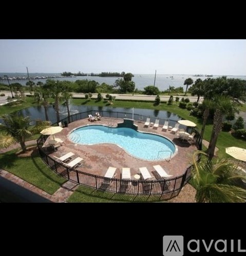A round pool surrounded by a fence and lounge chairs.