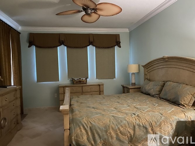 A bedroom with a bed, dresser, and window with curtains.