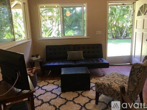 A living room with a black couch and a patterned ottoman.