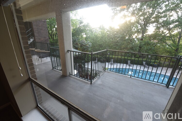 A balcony with a pool and trees in the background.