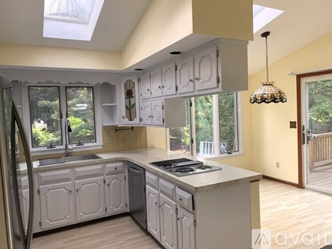 A kitchen with white cabinets and a stainless steel refrigerator.