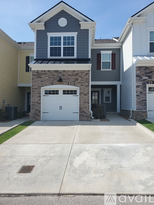 A house with a garage door and a stone wall.