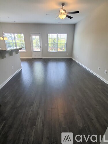 A spacious room with wooden floors and a ceiling fan.