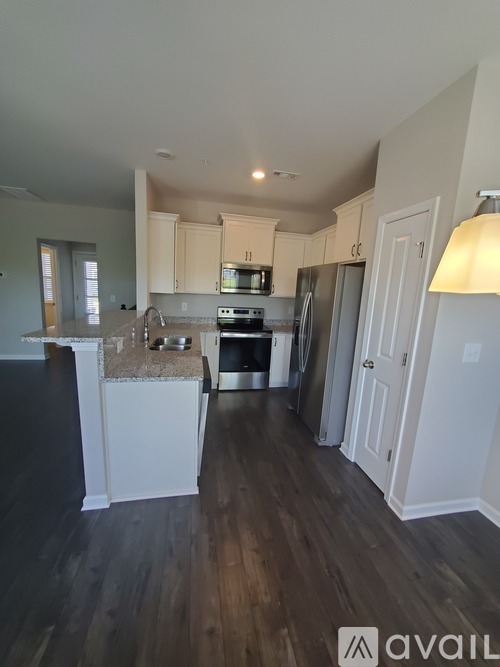 A kitchen with white cabinets and a wooden floor.