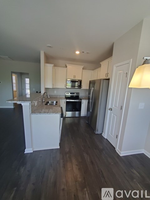 A kitchen with white cabinets and a wooden floor.