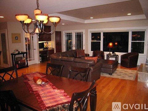 A living room with a brown couch and a chandelier.
