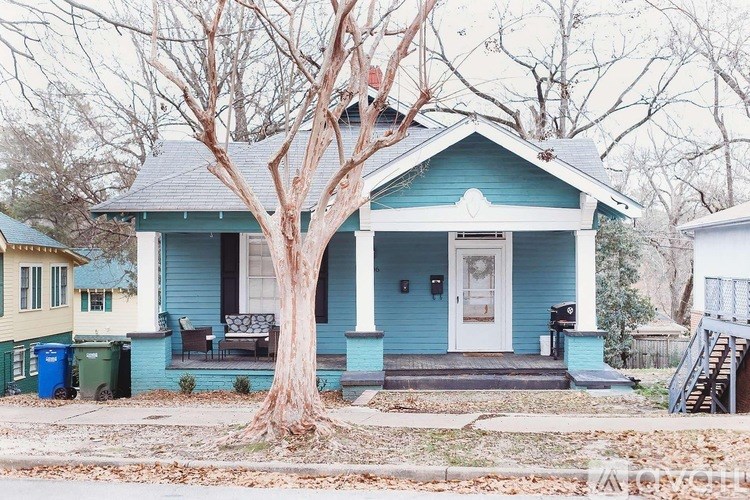 A blue house with a white door and a tree in front.